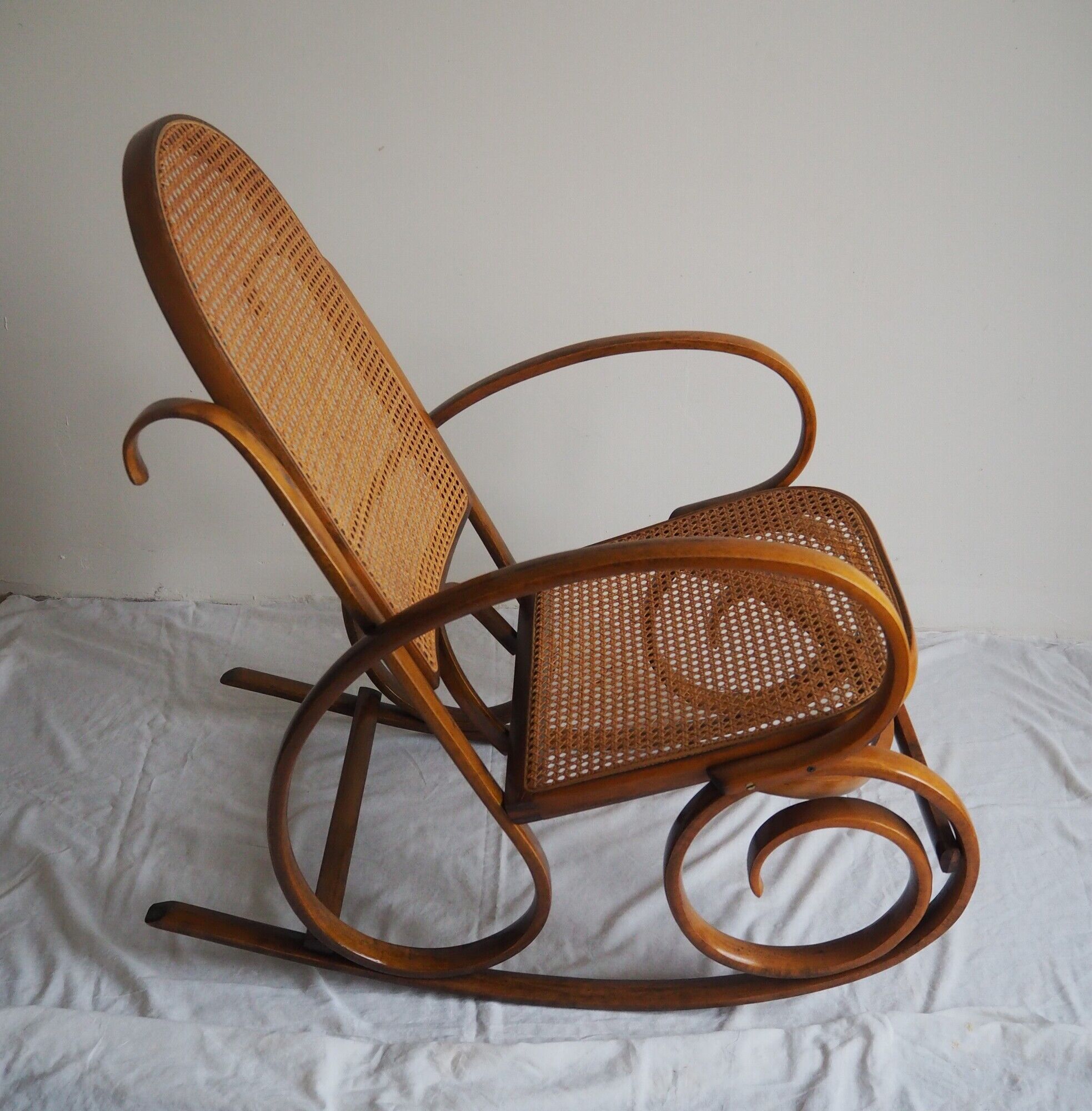 Rocking-chair en bois teinté et assise cannée