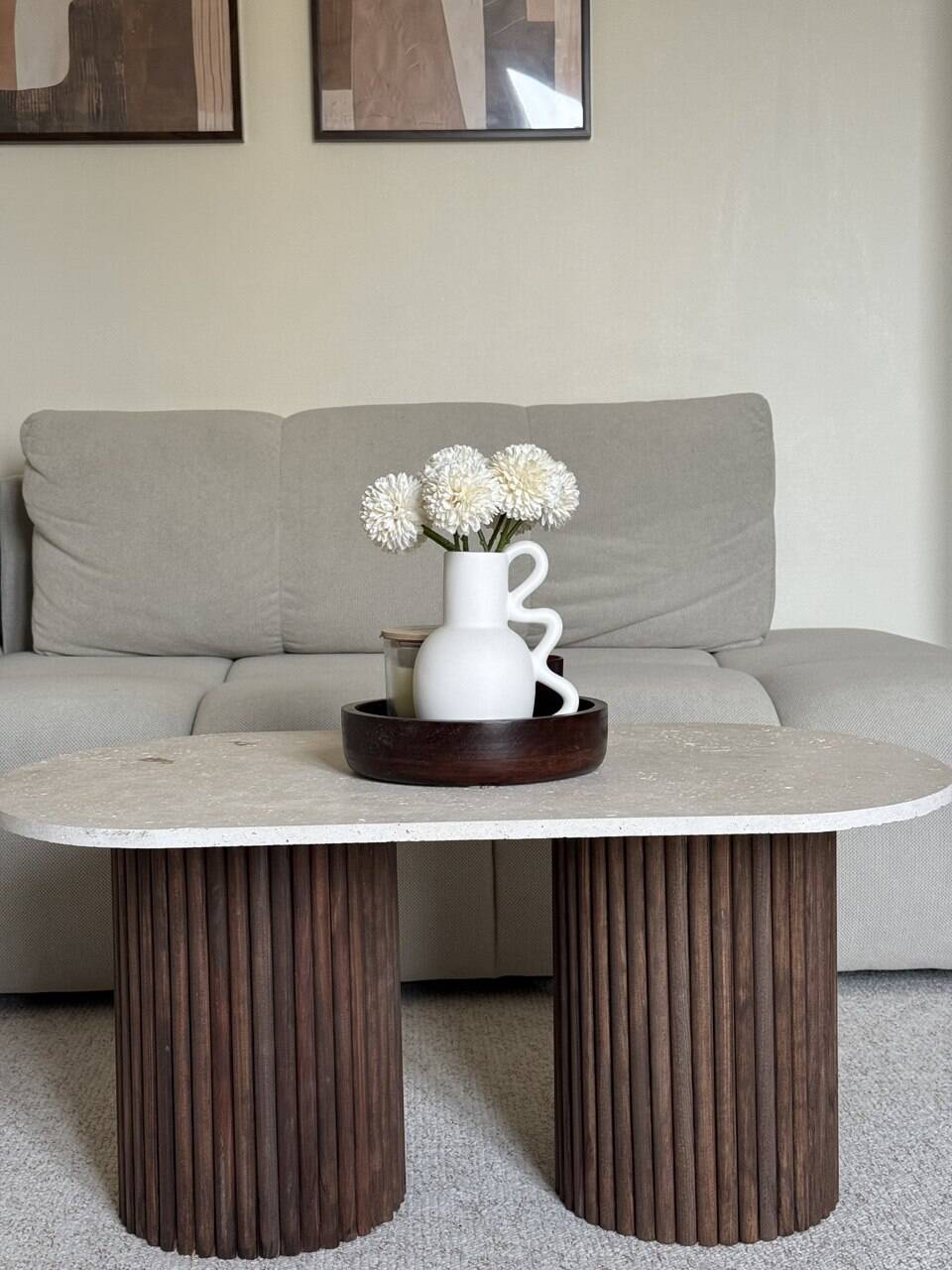 Oval coffee table in travertine and fluted wood.