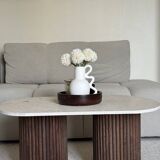 Oval coffee table in travertine and fluted wood.