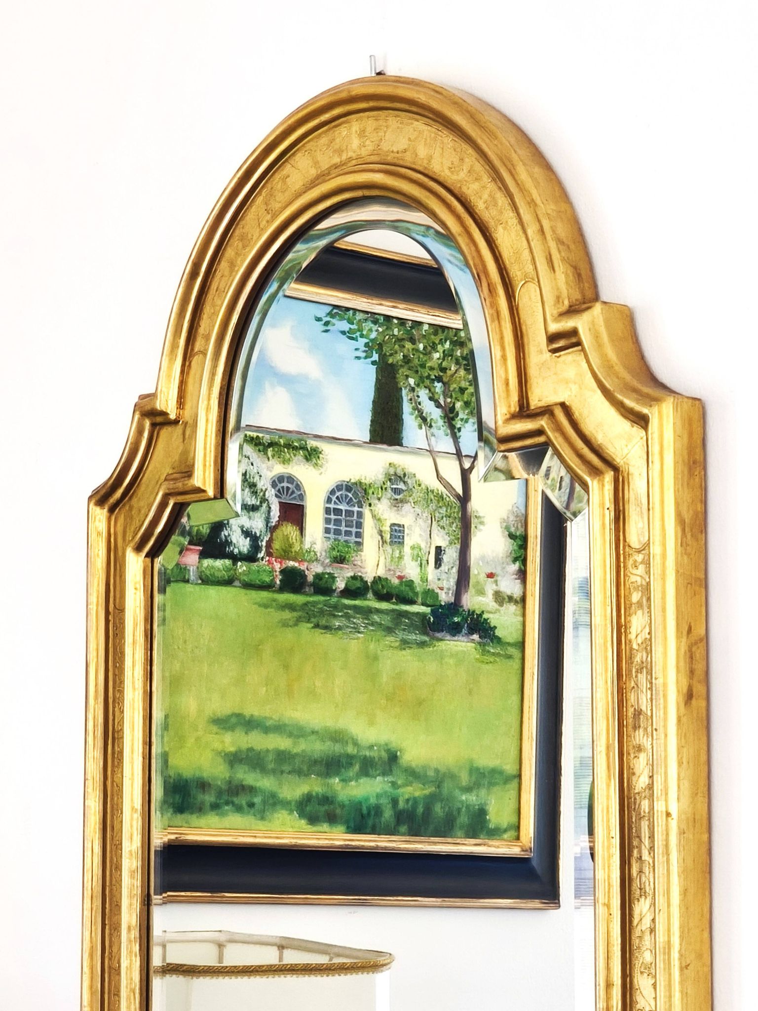Florentine arched mirror in gilded wood with gold leaf.