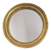 Round wooden mirror in golden colour.