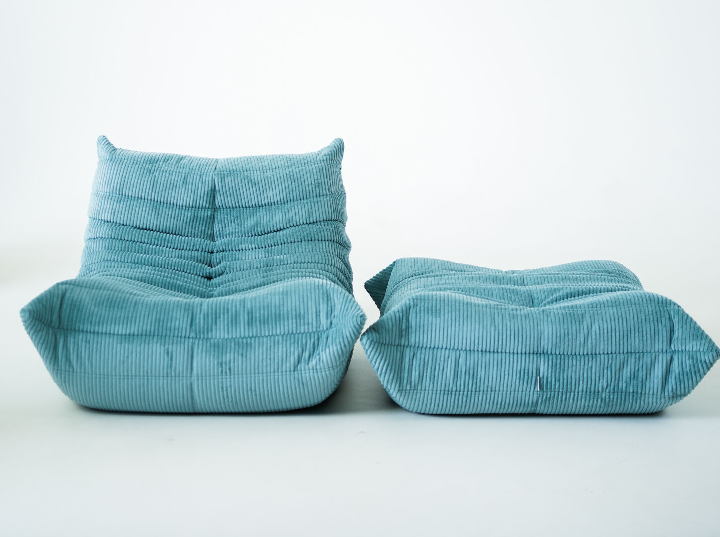 Ensemble de fauteuil et pouf Togo en velours côtelé bleu clair.