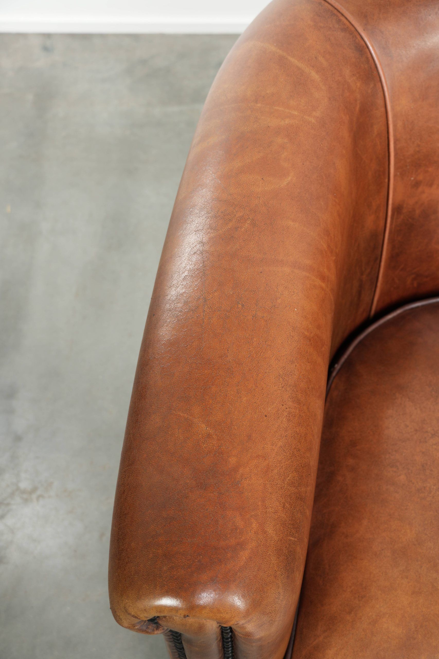 Sheepskin club armchair with a cognac colour finished with decorative nails