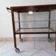 Art Deco brown wooden and glass bar cart, mobile display cabinet from the 1950s.