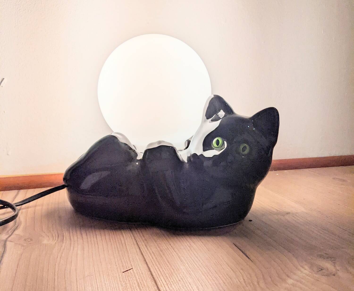 Black cat playing with its globe table lamp