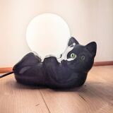 Black cat playing with its globe table lamp