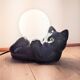 Black cat playing with its globe table lamp
