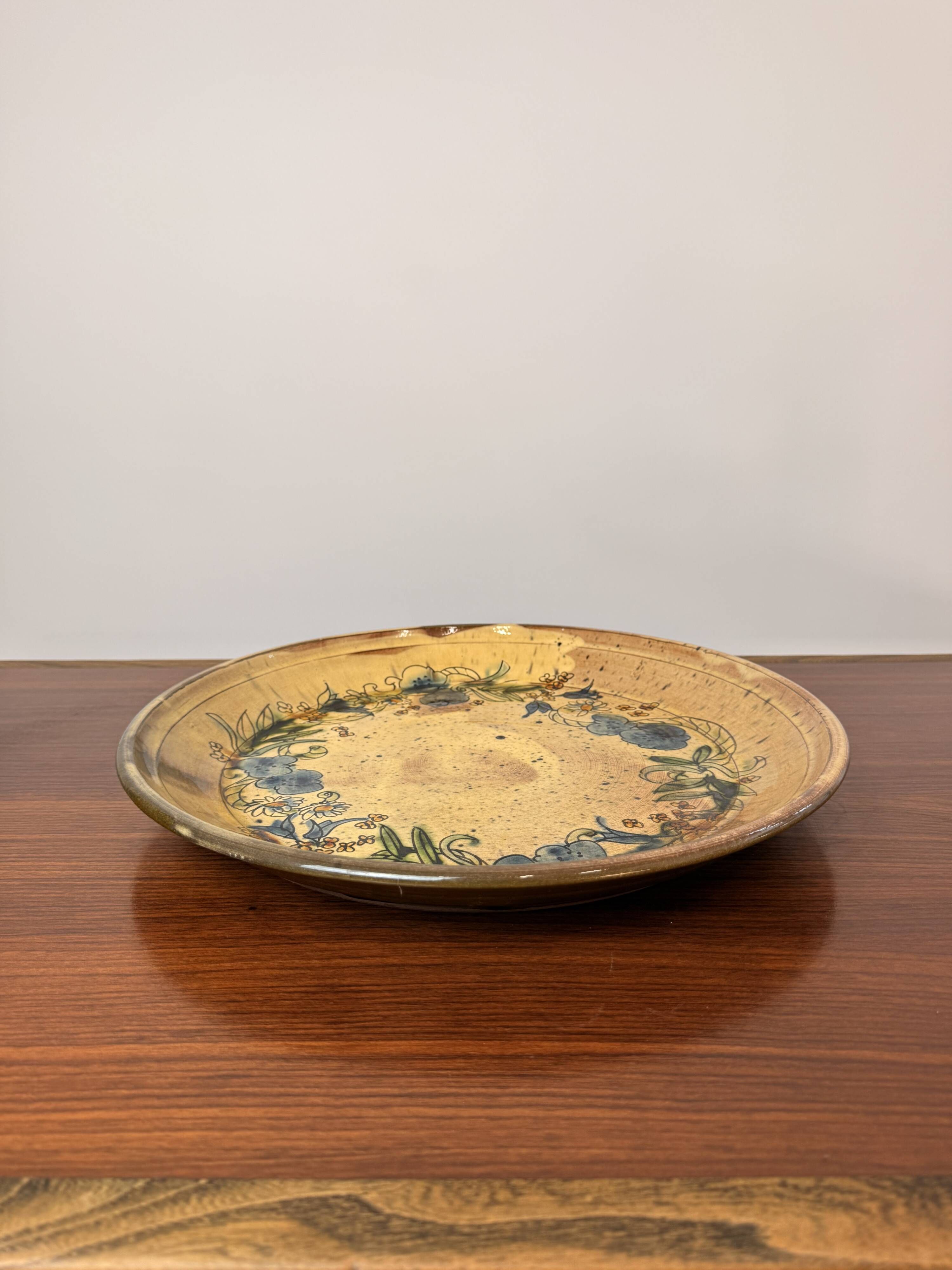 Vintage round ceramic plate with floral decoration.
