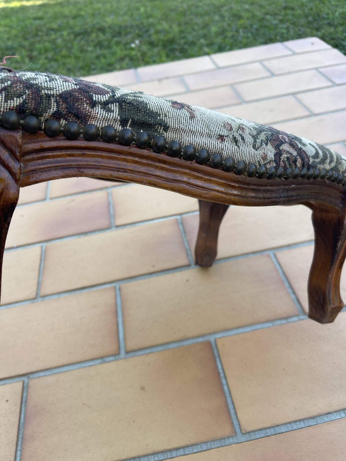 Antique wooden footstool with hand-carved details and floral upholstery –