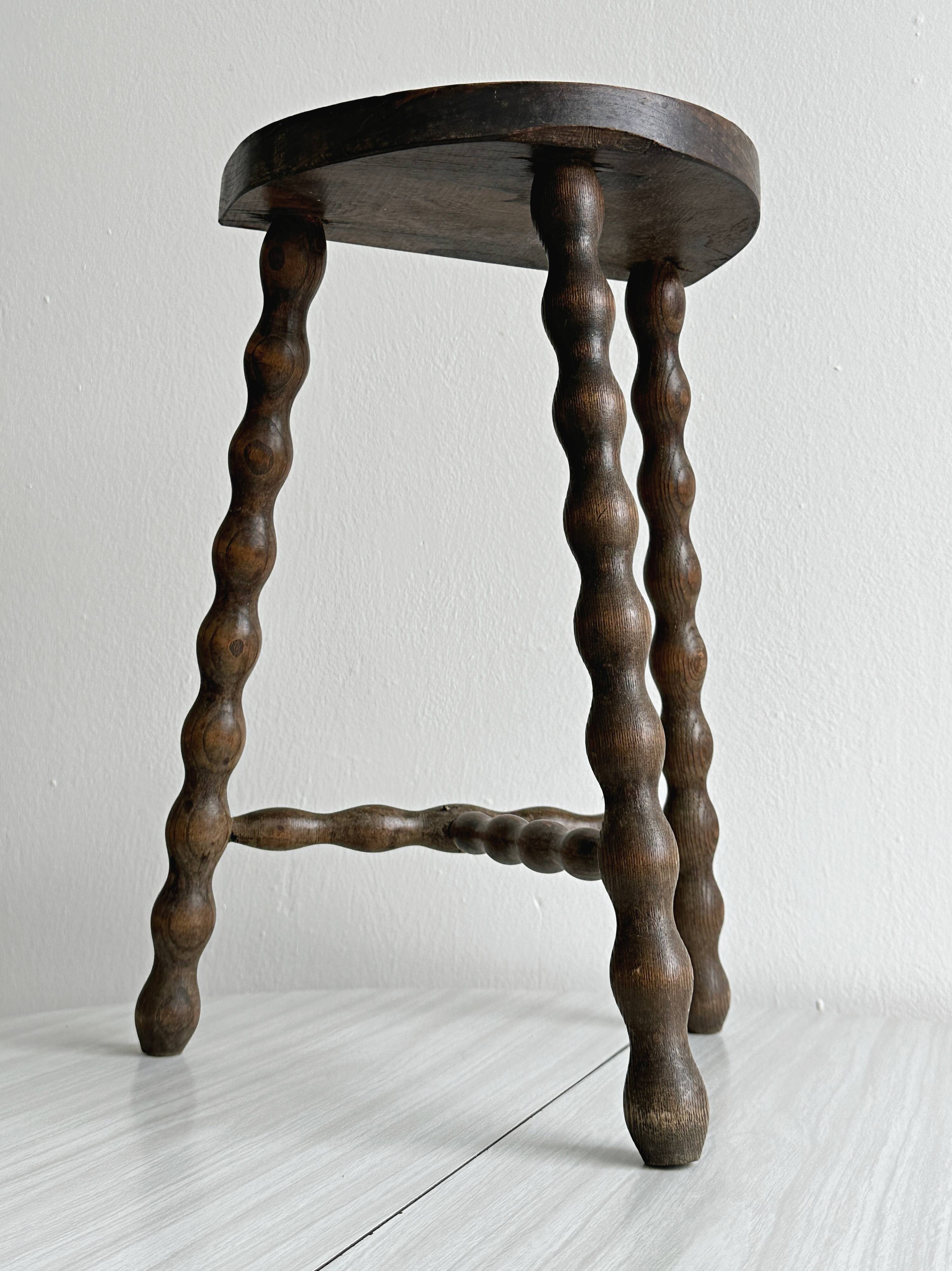 Three-legged demi-lune stool made of turned wood