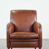 Cognac-colored sheepskin armchair with rounded shapes