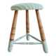 Antique tripod stool with striped seat.