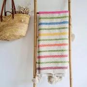 Moroccan plaid made of handwoven wool, decorated with stripes and pom-poms.