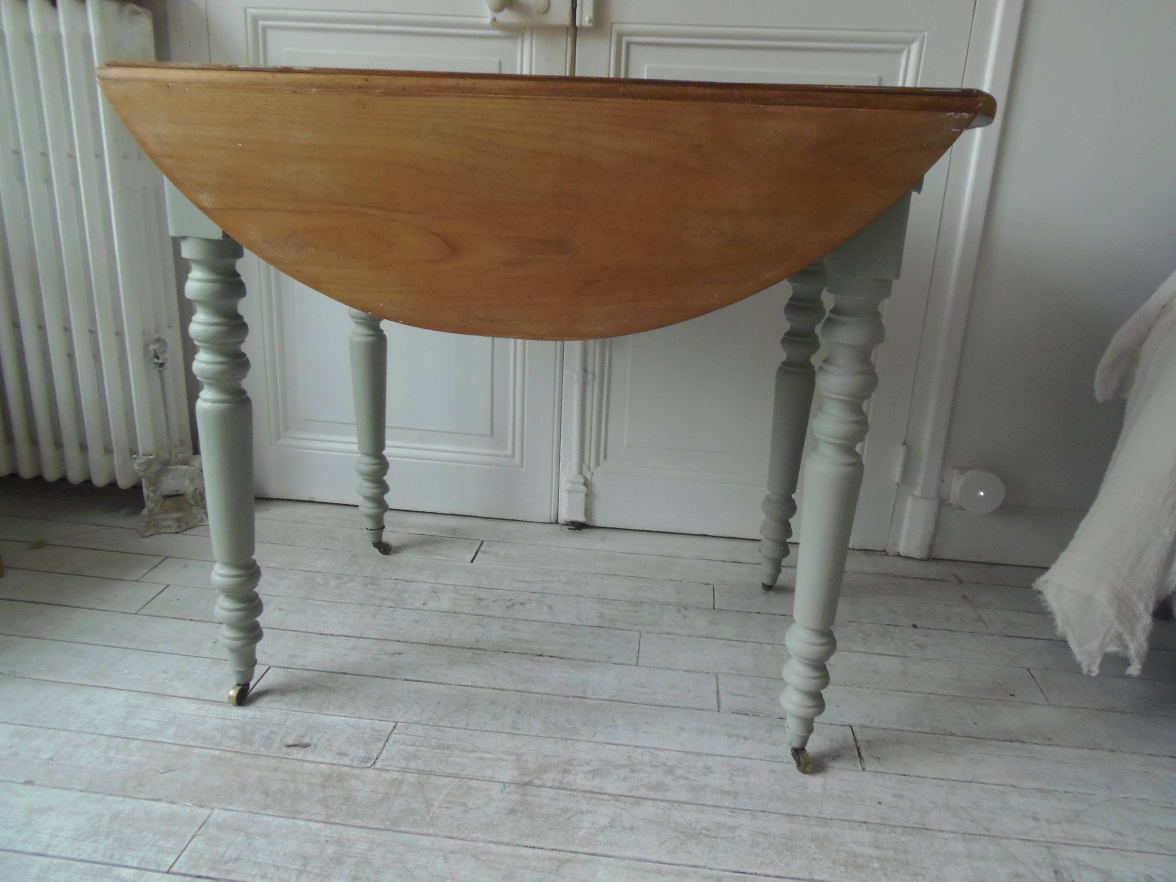 Raised walnut table with drop-leaf top, base on verdigris castors.