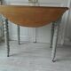 Raised walnut table with drop-leaf top, base on verdigris castors.