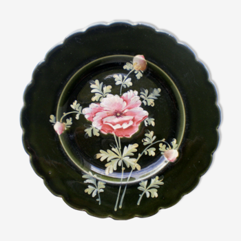 Old plate decorated with anemones or poppies on a black background