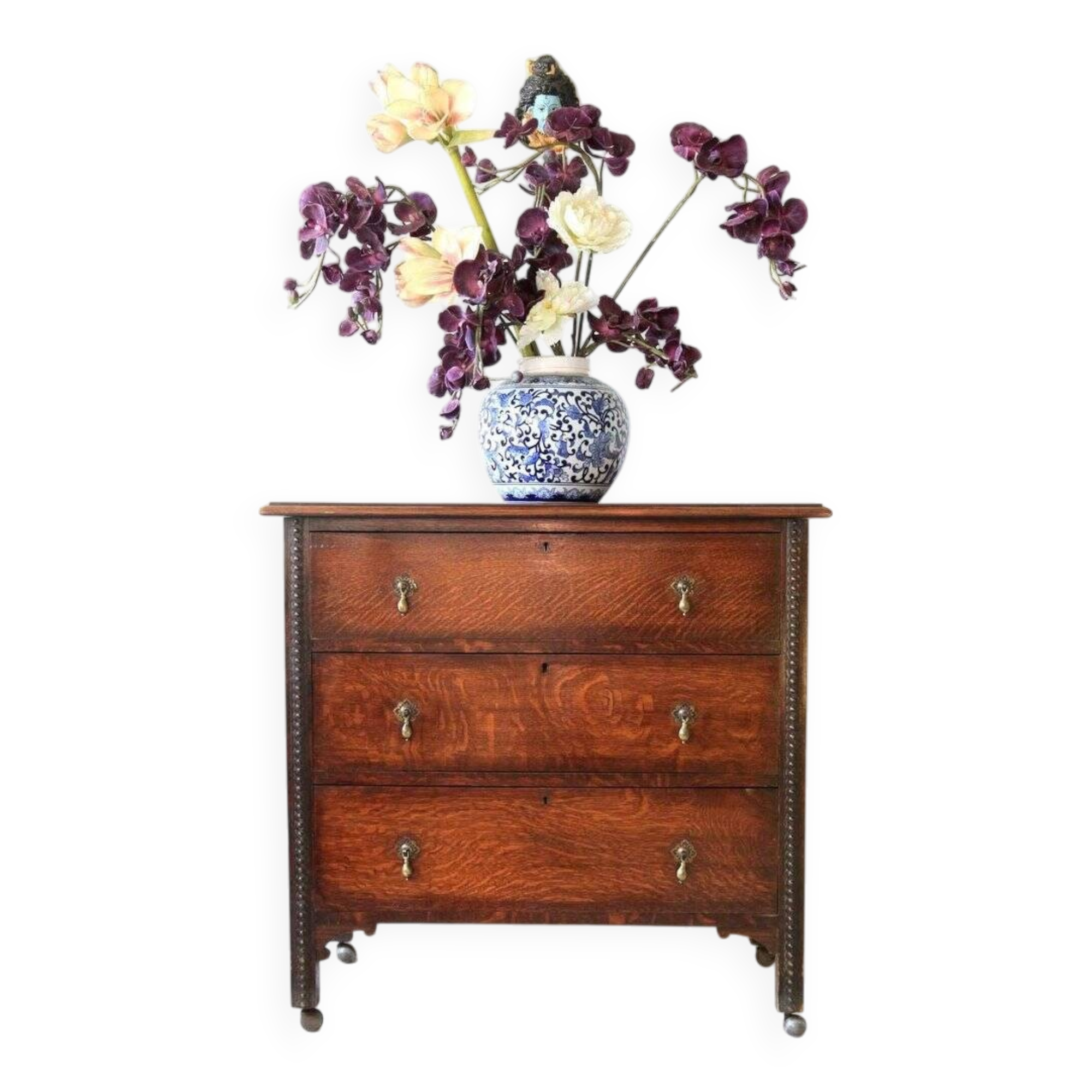 Antique oak chest of drawers on castors with brass handles and carved details