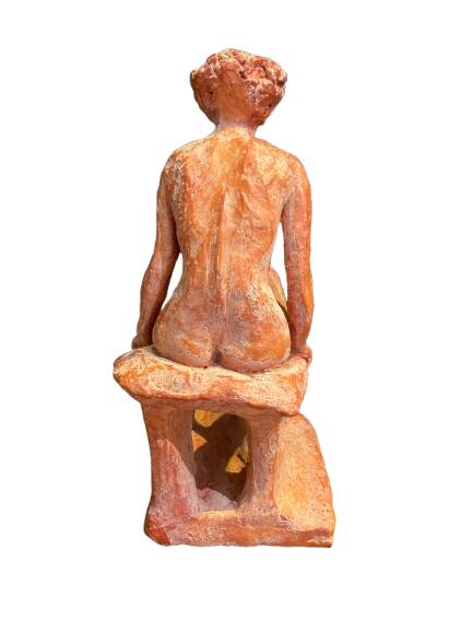 Painted plaster sculpture of a nude woman on a bench