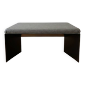Minimalist/industrial coffee table with a black metal frame and a grey fabric top.
