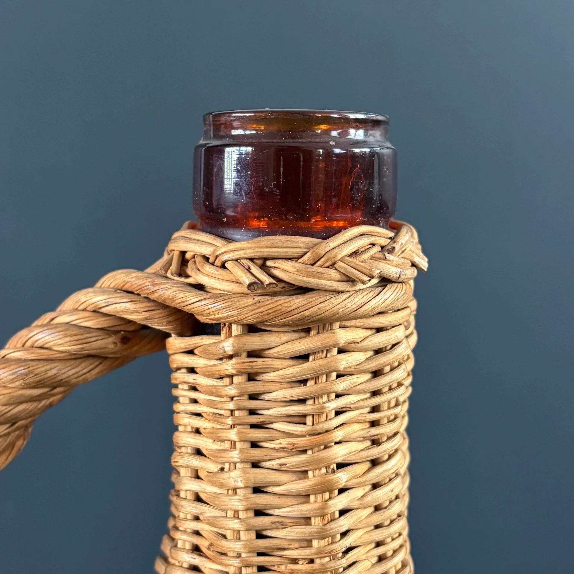 Amber glass bottle in its wicker handle basket.
