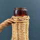Amber glass bottle in its wicker handle basket.