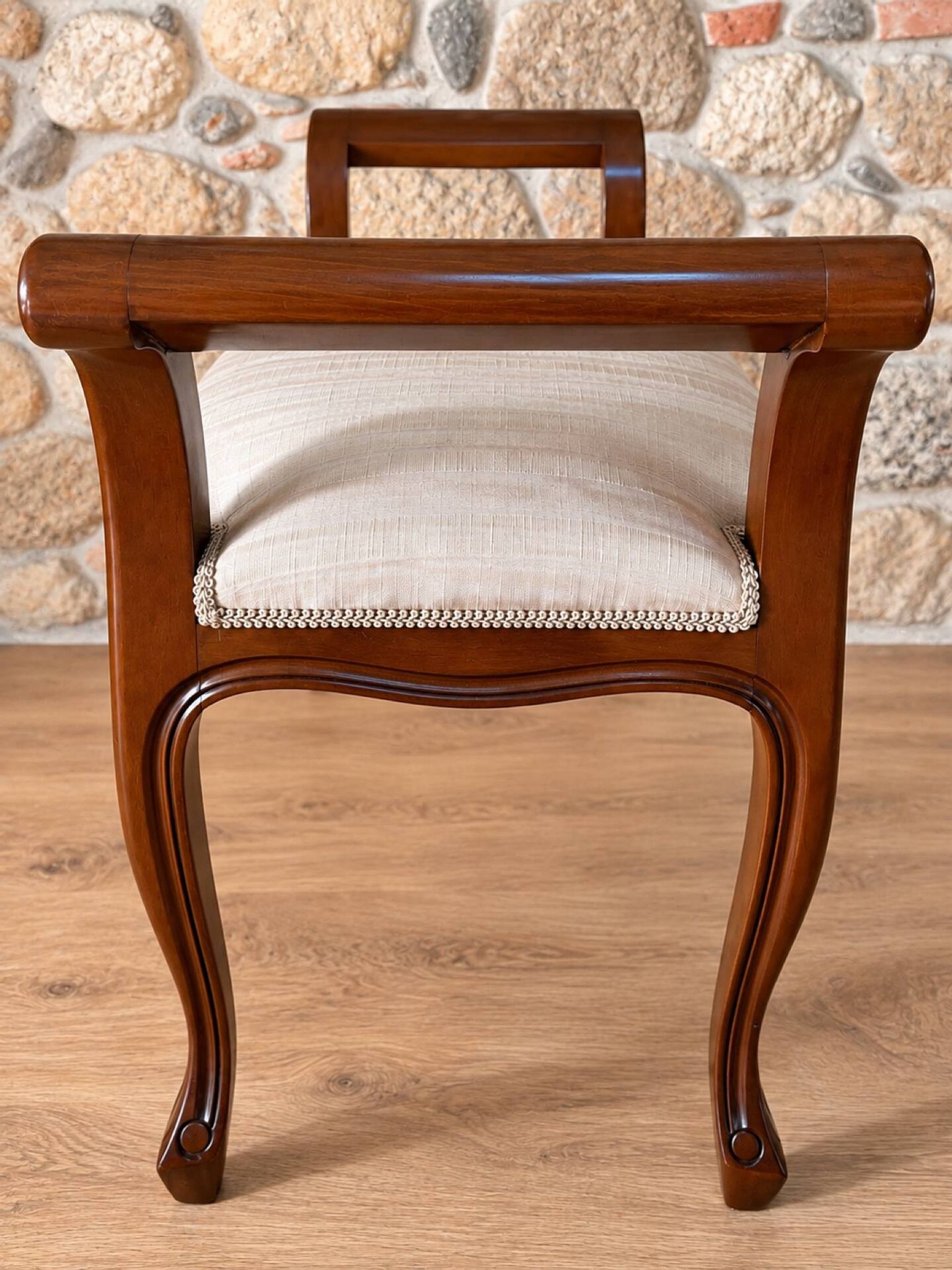 Two-seater bench in carved wood, with curved armrests.