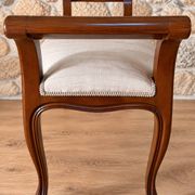 Two-seater bench in carved wood, with curved armrests.