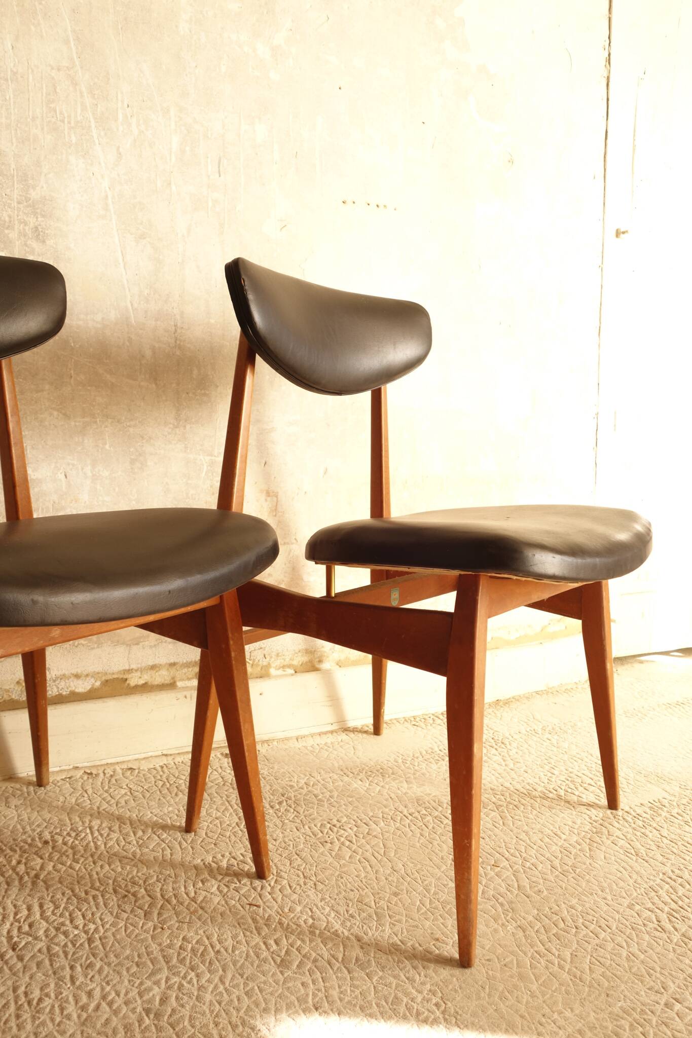 Pair of modernist Scandinavian chairs in teak and black faux leather.