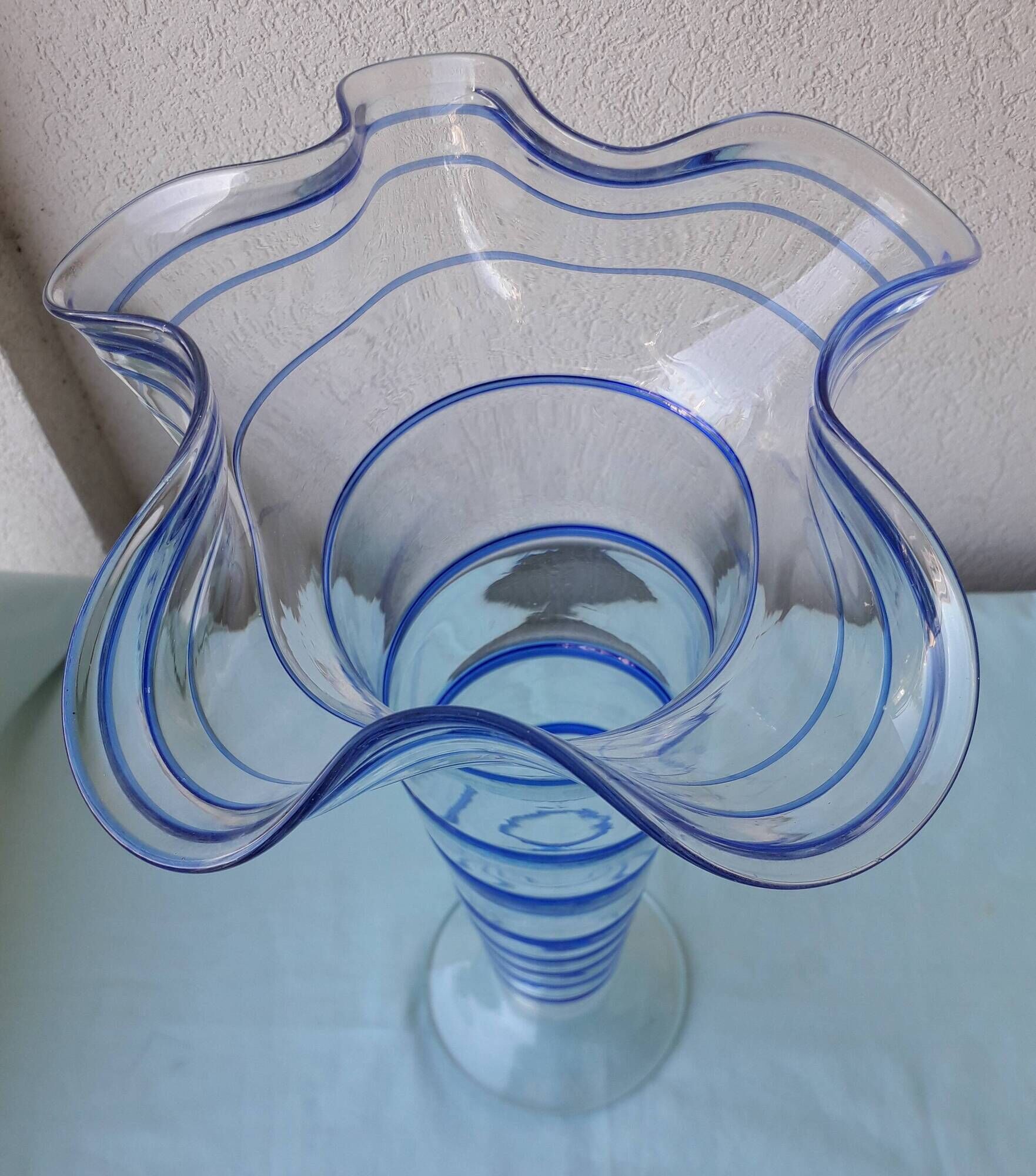 Glass vase on a pedestal with a blue trim.