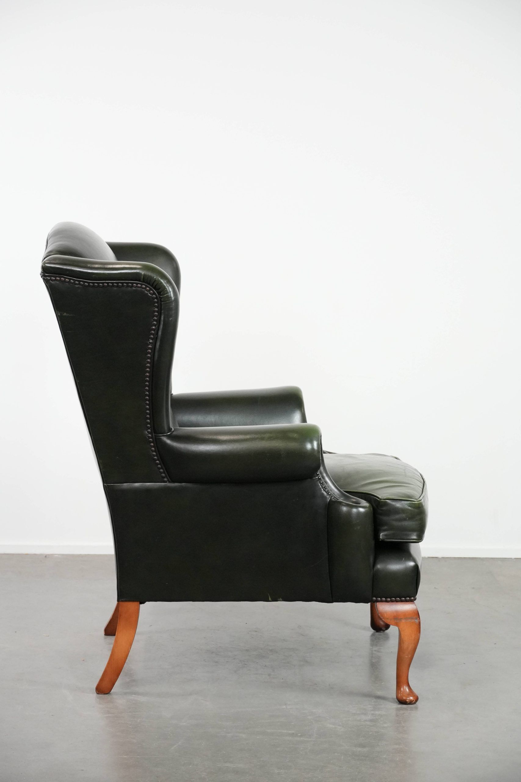 Smooth classic cowhide Chesterfield armchair in a stylish dark green color