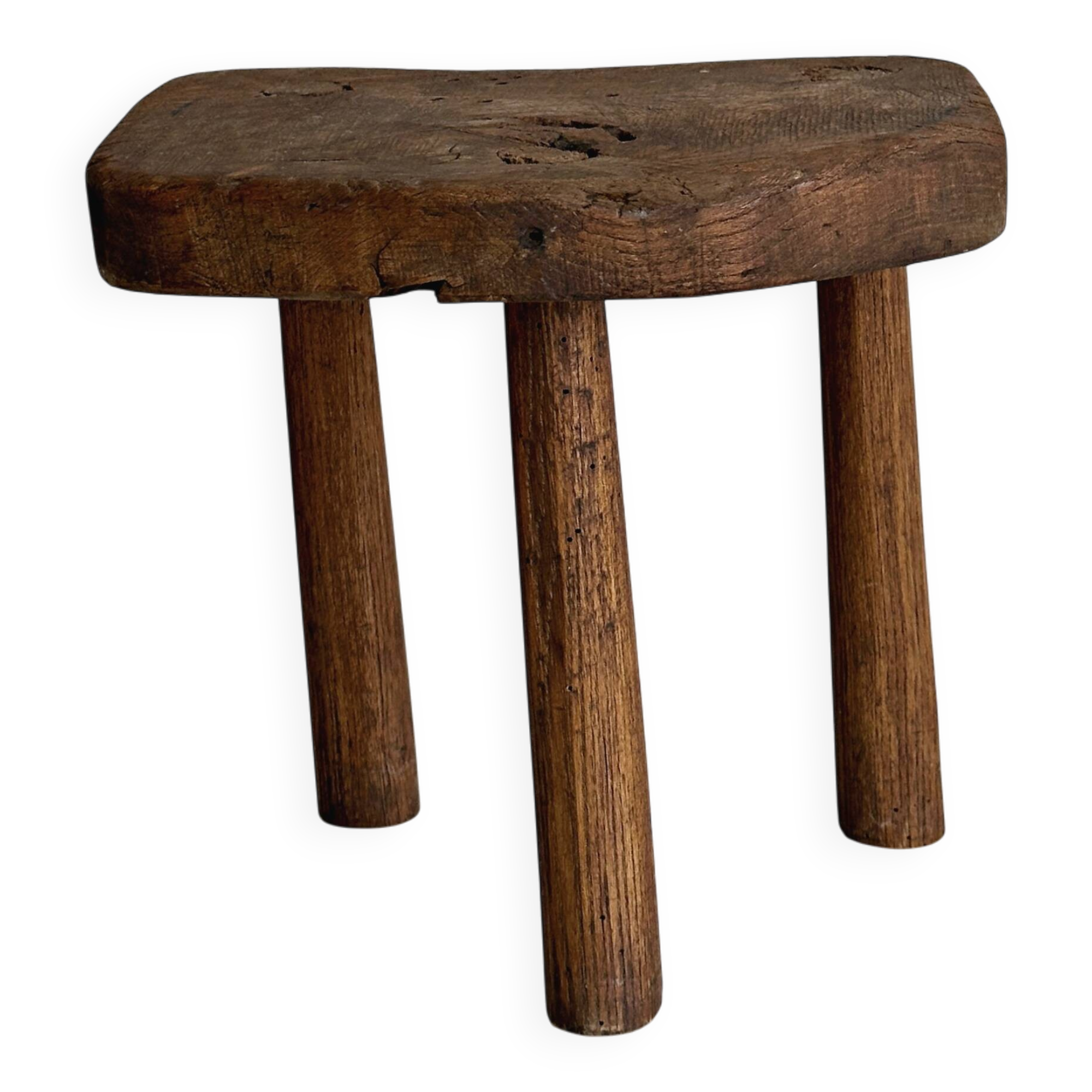 Antique three-legged stool made of raw solid wood.