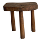 Antique three-legged stool made of raw solid wood.
