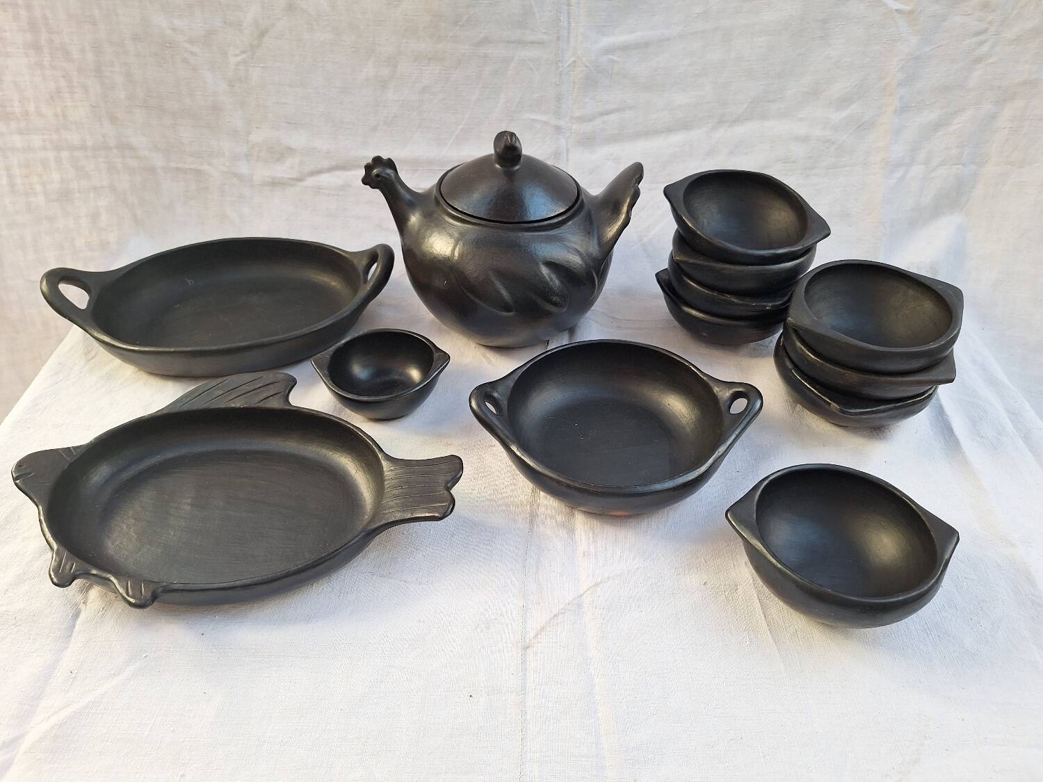 Black terracotta dinnerware set from La Chamba in Colombia. Set of 13 pieces.