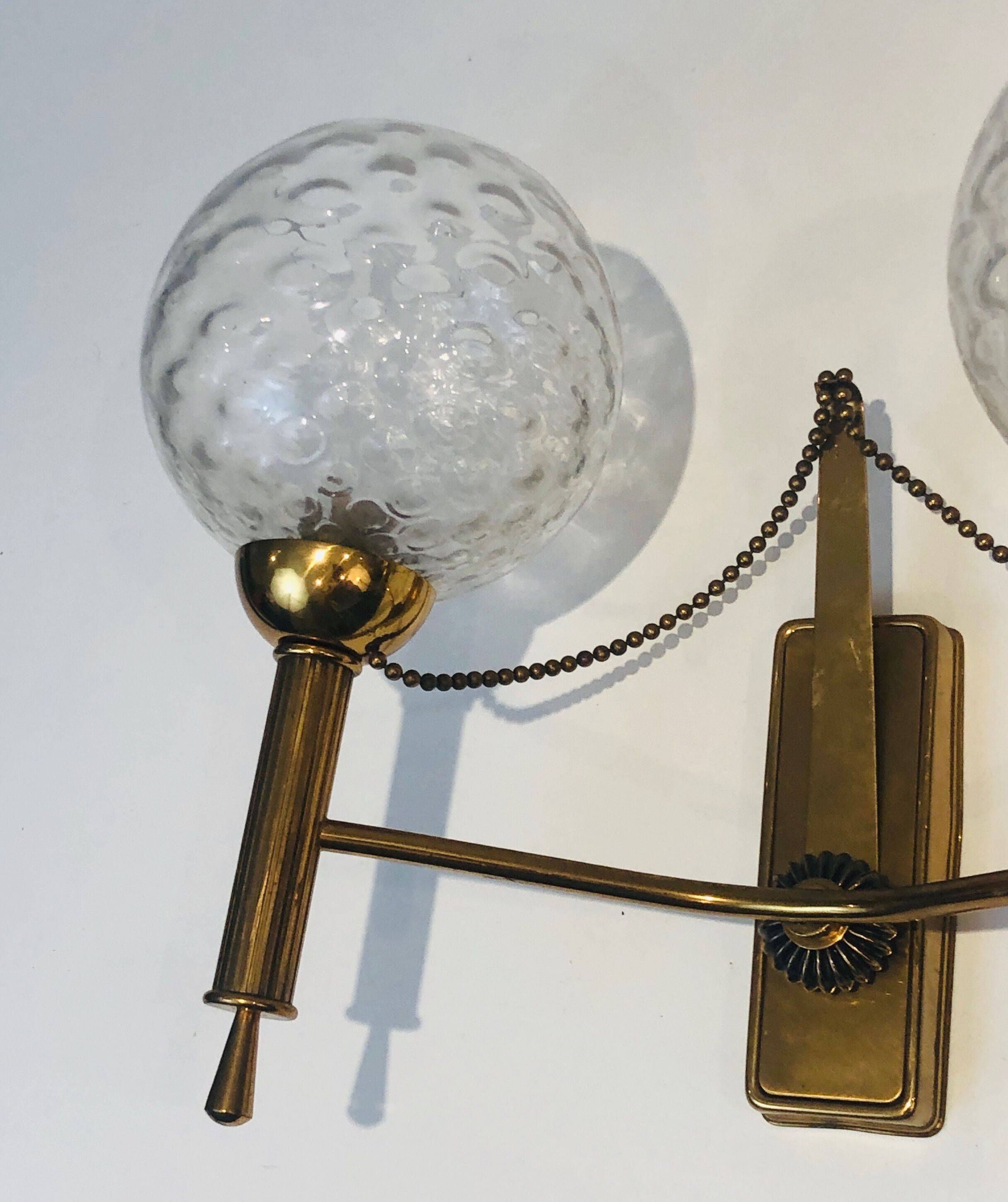 Pair of brass wall lights with glass globes. Around 1970.