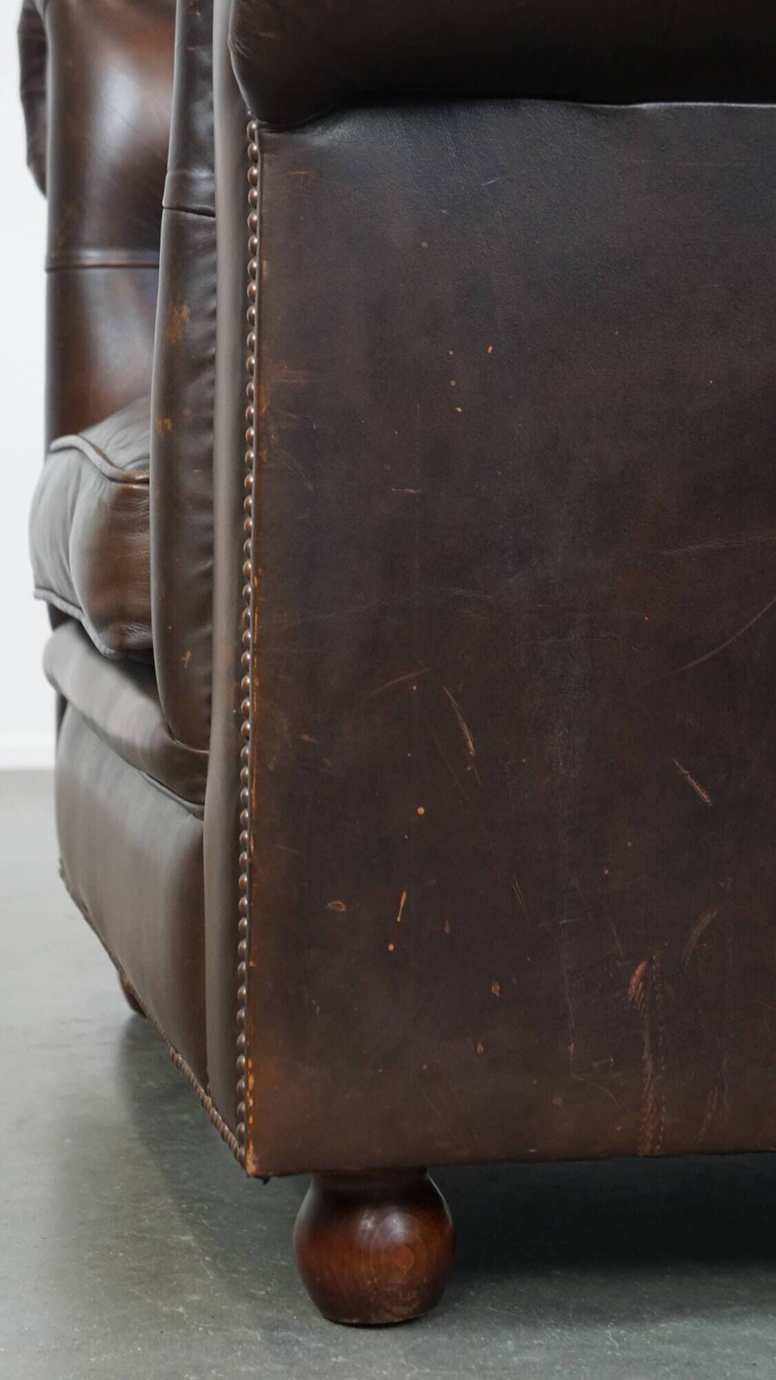 Cowhide English Chesterfield armchair with ball legs and timeless finish