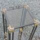 Pair of Hollywood Regency side tables in gold metal and smoked glass.