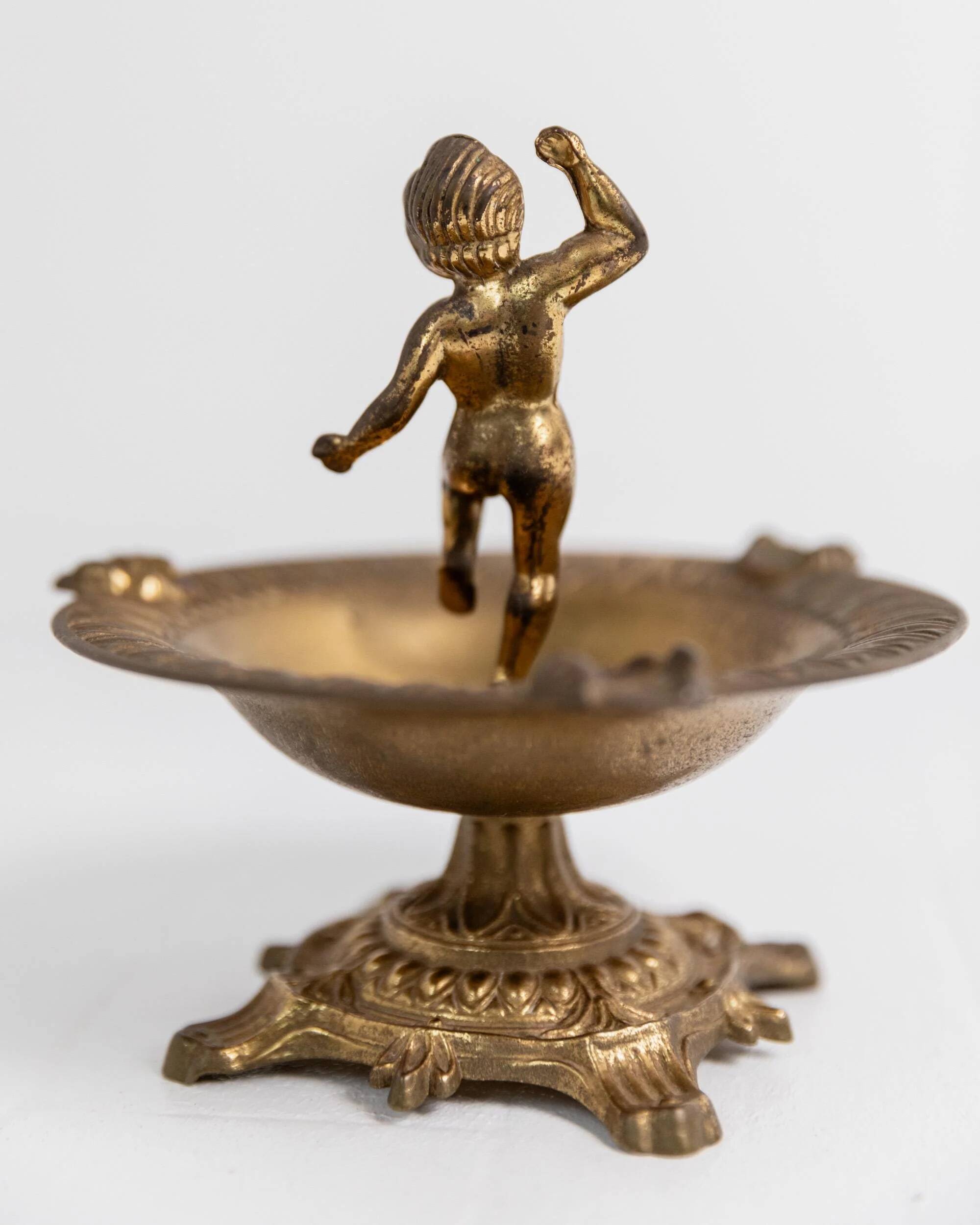 Vintage brass ashtray from the 1940s with a nude boy figurine on a footed base.