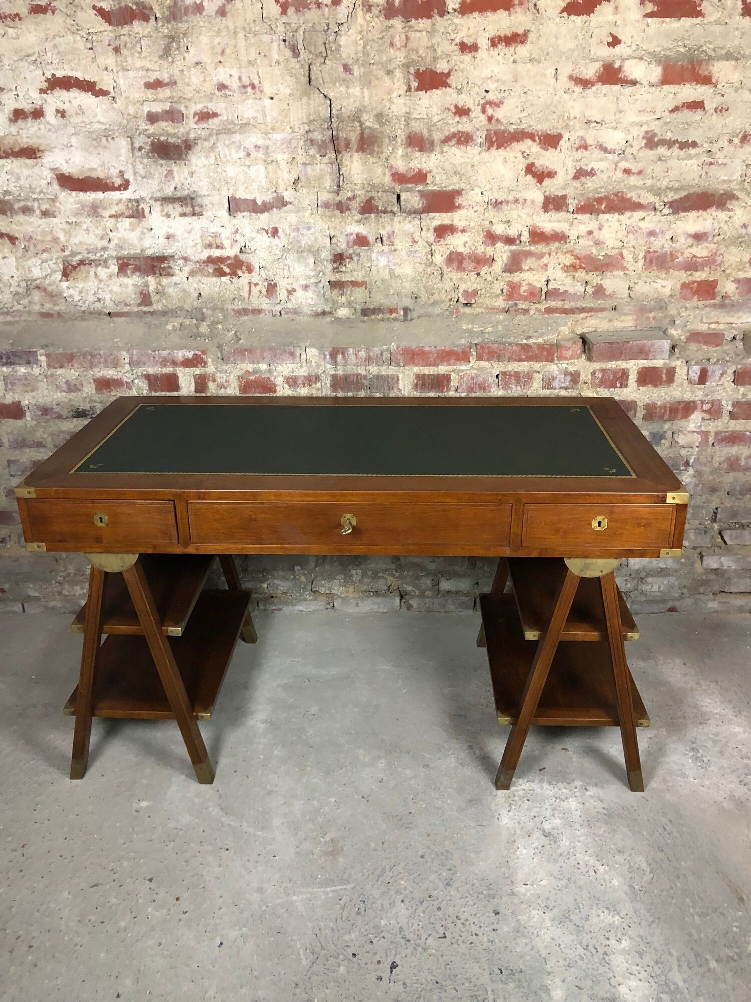 Walnut desk with green leather top resting on two trestles