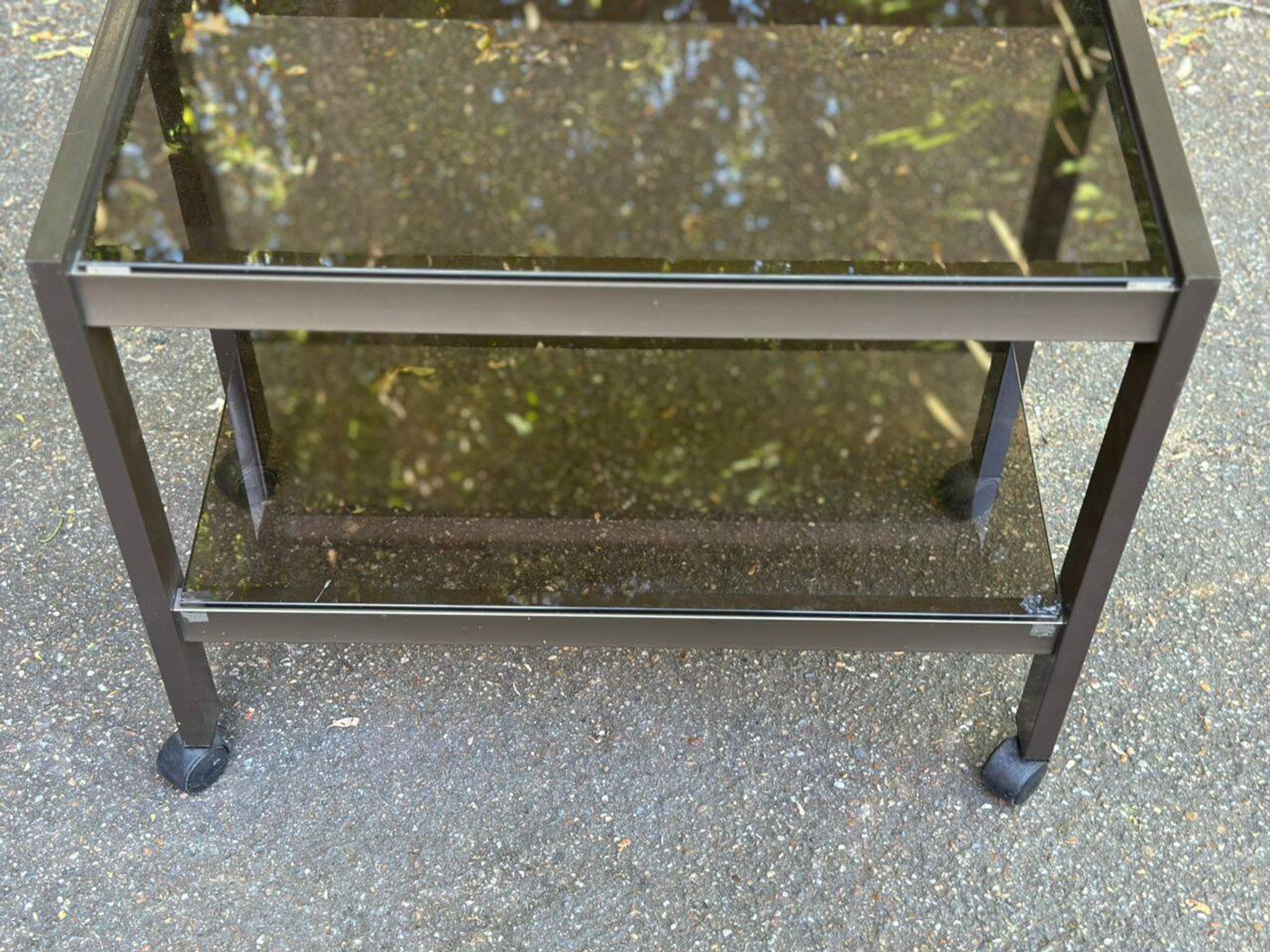 Vintage 1970s rolling bar cart made of metal and smoked glass.