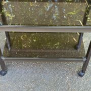 Vintage 1970s rolling bar cart made of metal and smoked glass.