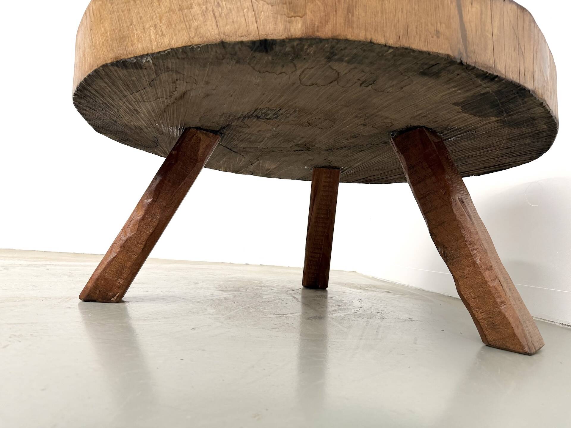 Brutalist coffee table in solid teak, monolithic slab, tripod base.