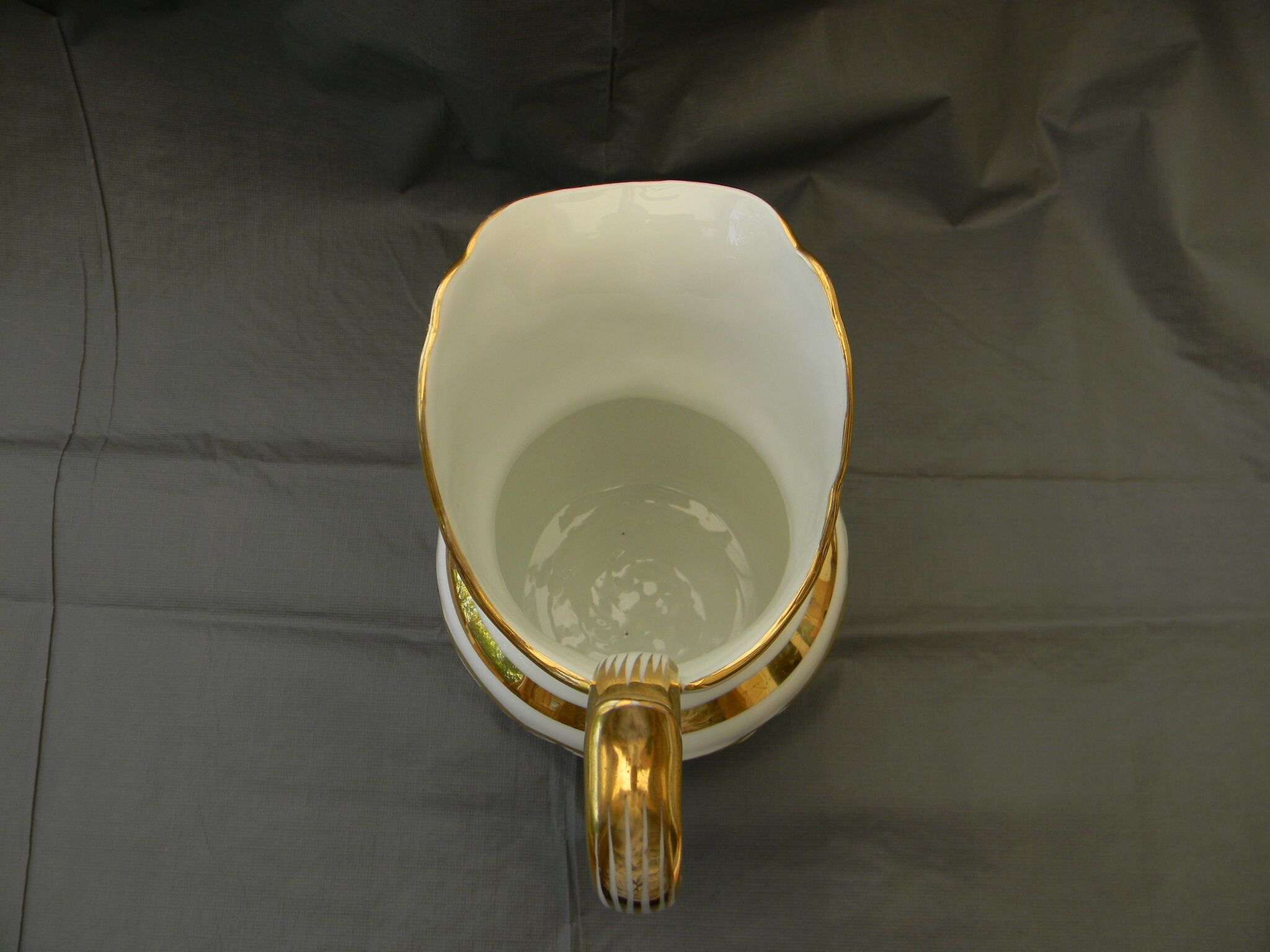 Milk jug or antique pitcher in white and gold porcelain.