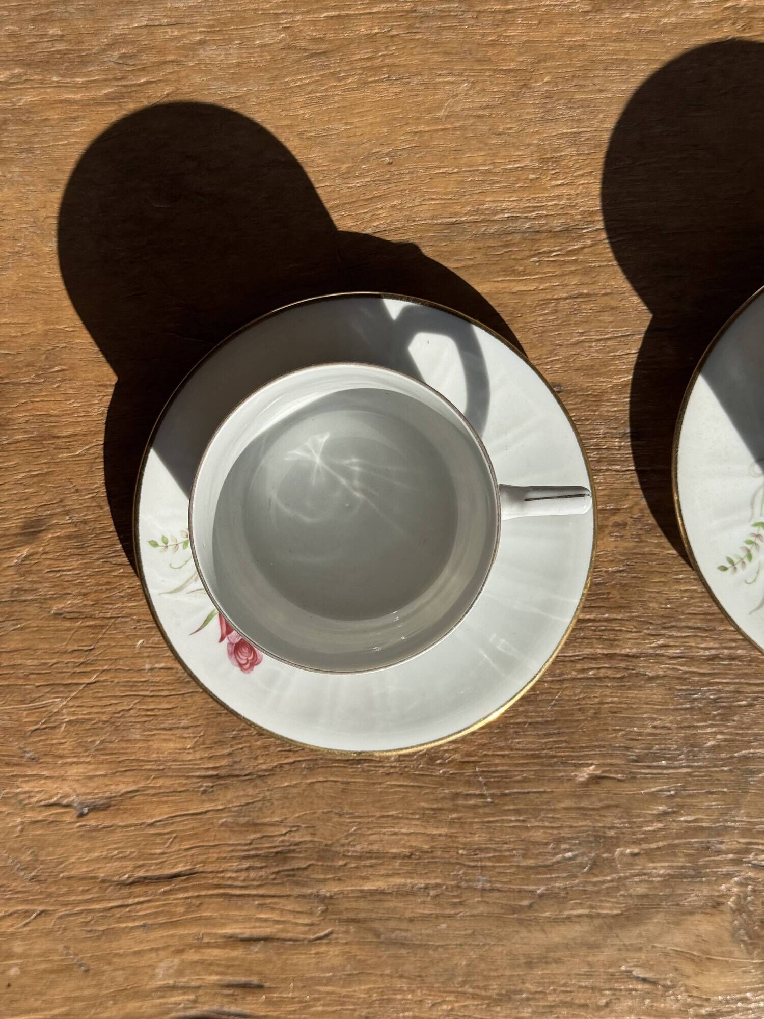 Pair of white porcelain cups from ADP France with a floral pattern and their s