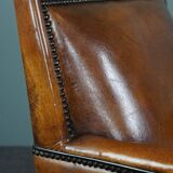 Art deco armchair in sheepskin with black piping and decorative nails