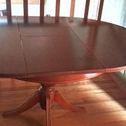 Round solid walnut table with central leg from the 1950s with extensions.