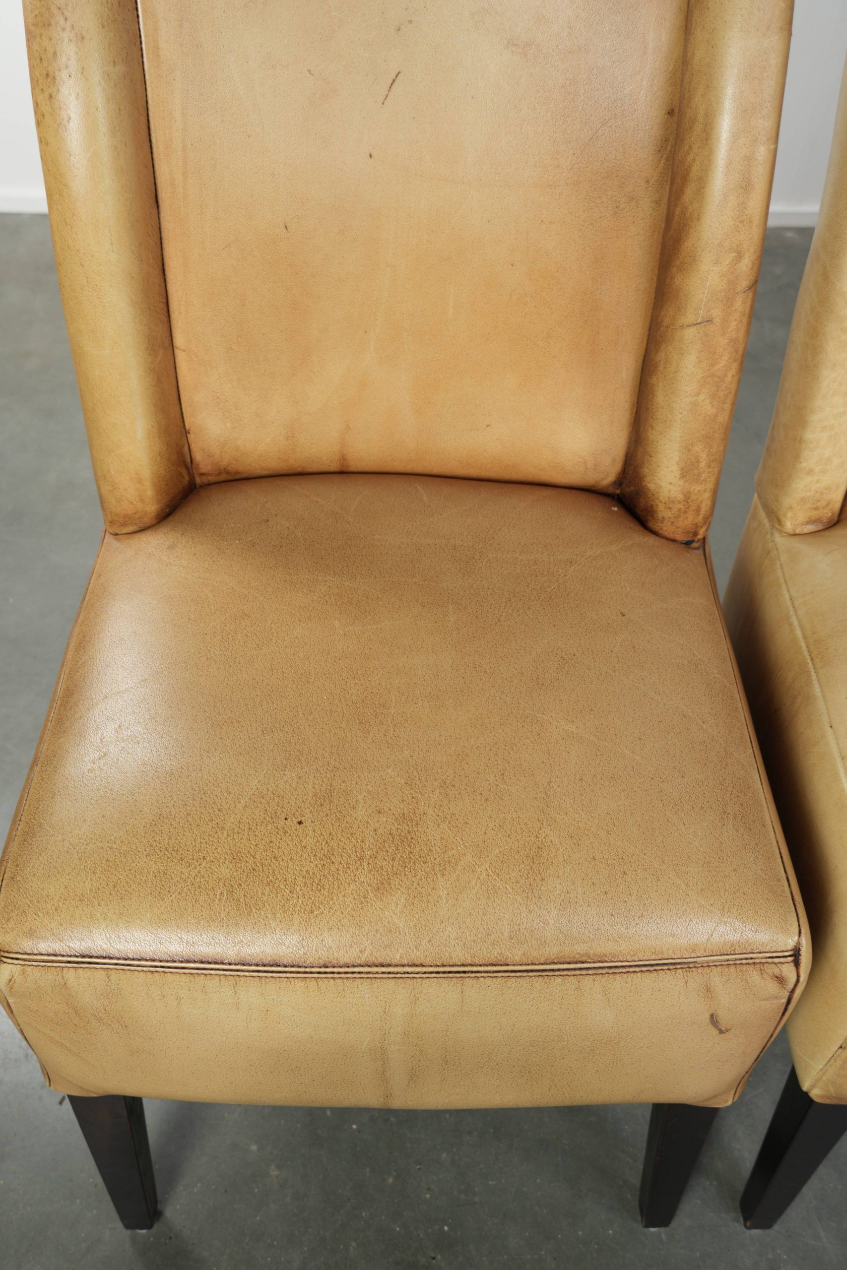 Ensemble de quatre chaises de salle à manger en cuir de vache avec un siège confortable et un dossier haut.