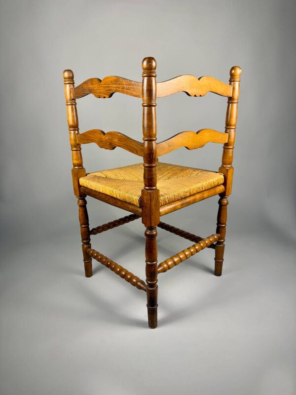 Chaise d'angle vintage en bois avec assise en paille tissée.