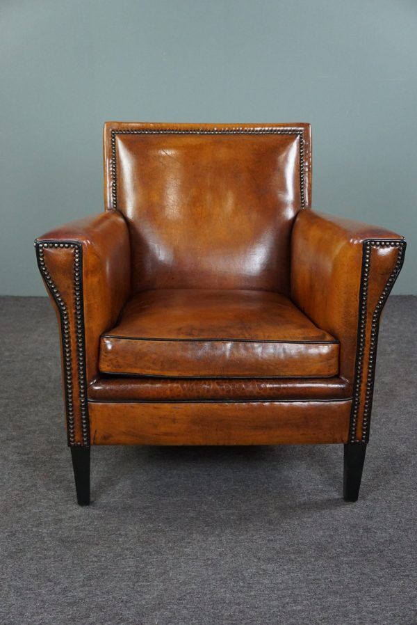 Art deco armchair in sheepskin with black piping and decorative nails