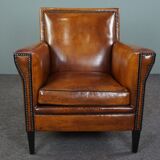 Art deco armchair in sheepskin with black piping and decorative nails