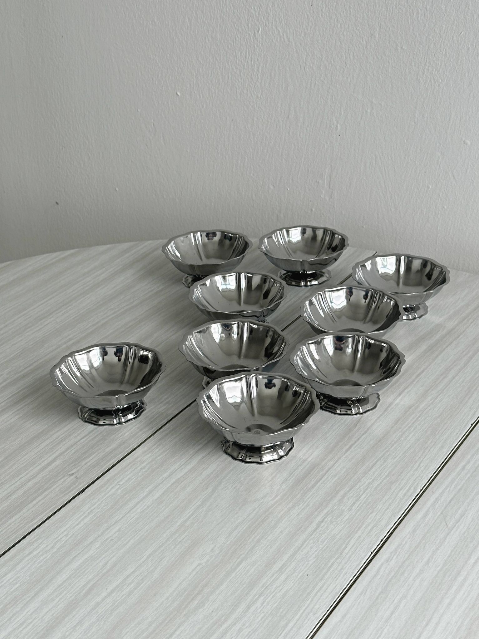 Set of 9 low bowls in shiny stainless steel.
